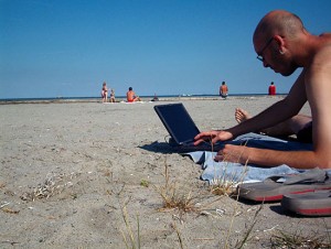 Man using laptop on beach