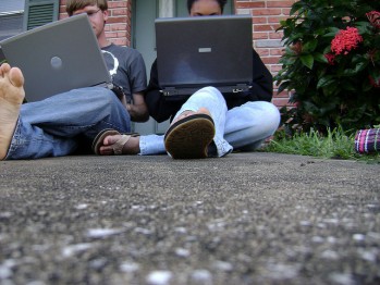 Two boys sitting outside using laptop